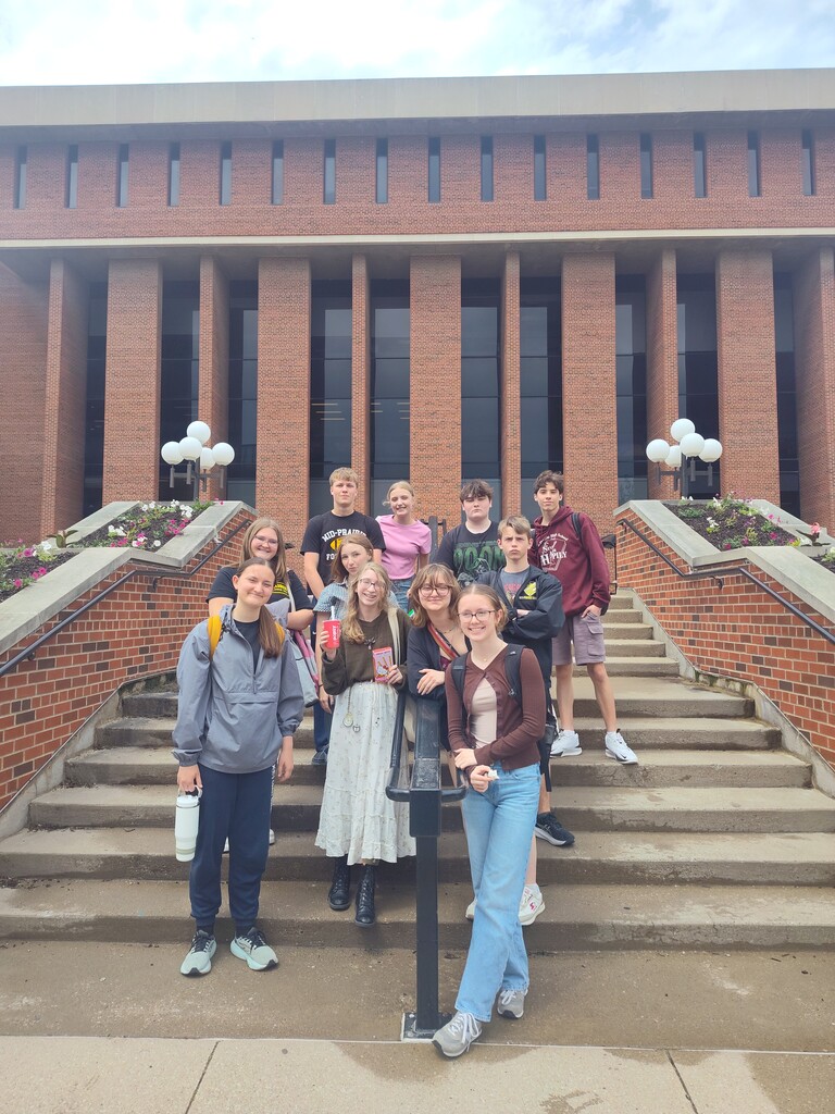 Group of high school students standing together and smiling in front of the University of Iowa Main Library