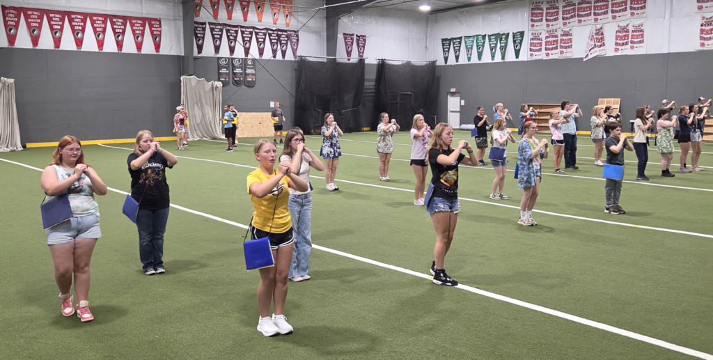 MP marching band students in the MP indoor facility practicing on the turf