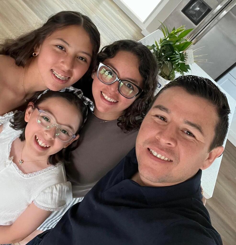 Cinthia with husband and two daughters smiling