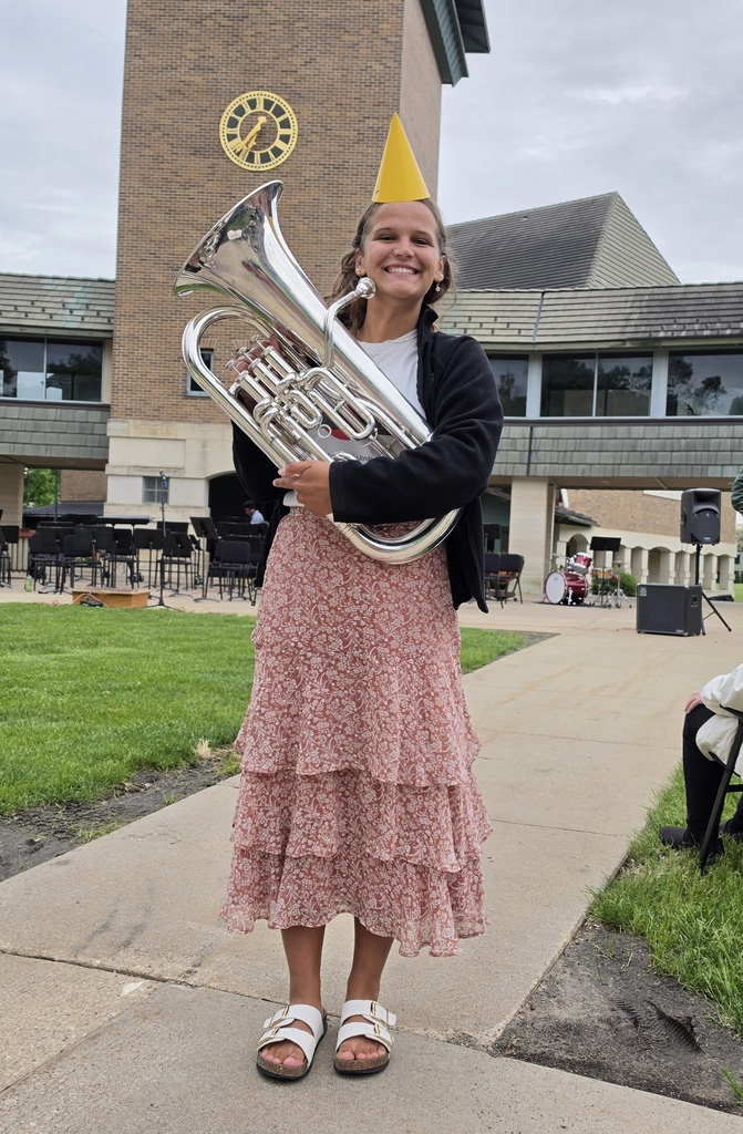 Haley Hansen holding a silver instrument and wearing a red flowered dress smiling outdoors
