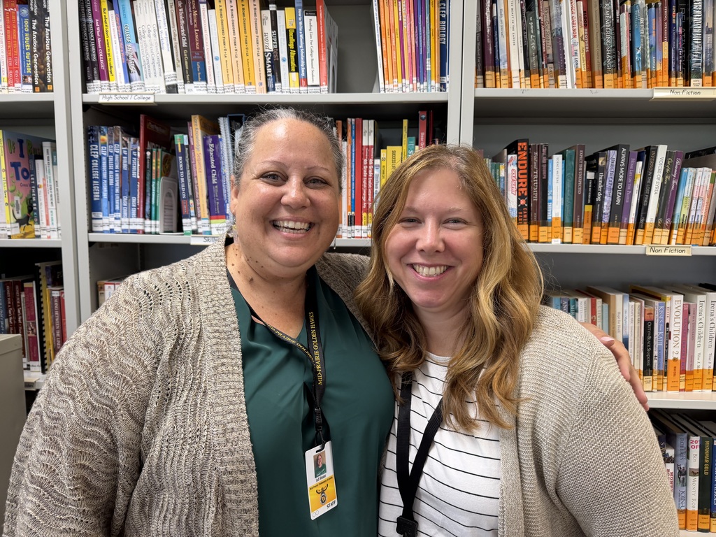 Jodi Meader and Beryl Marner smiling standing in front of library shelves full of books