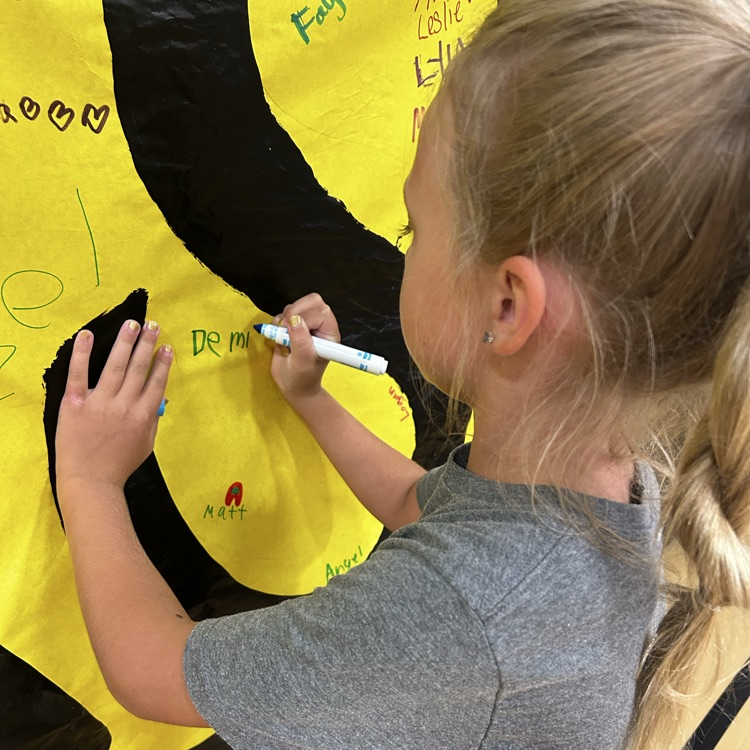 student writing her name on banner