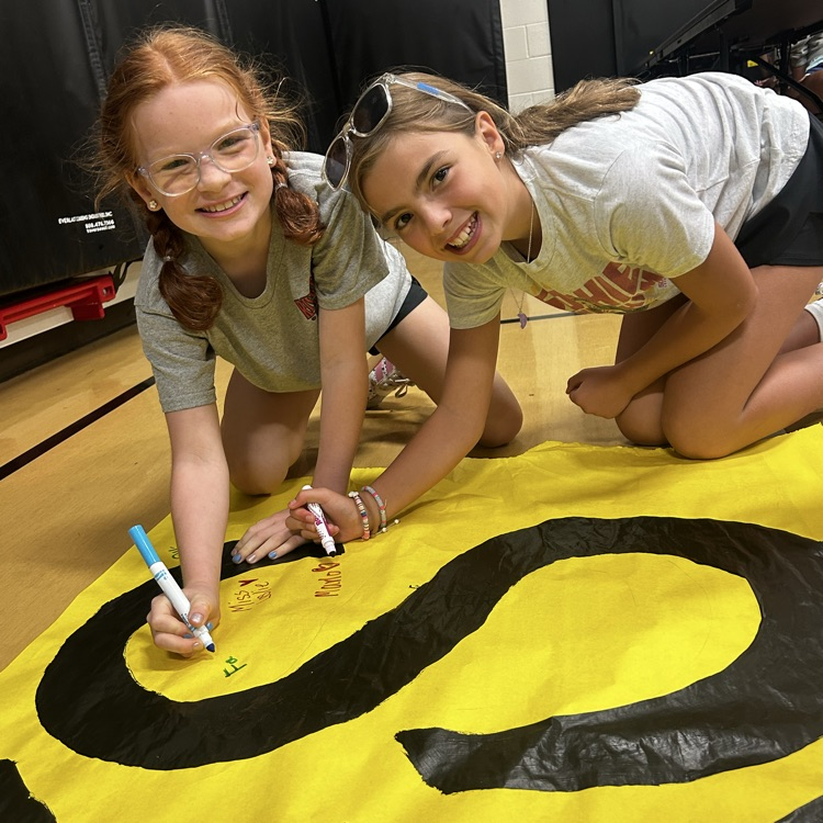 students smiling while writing their name on banner