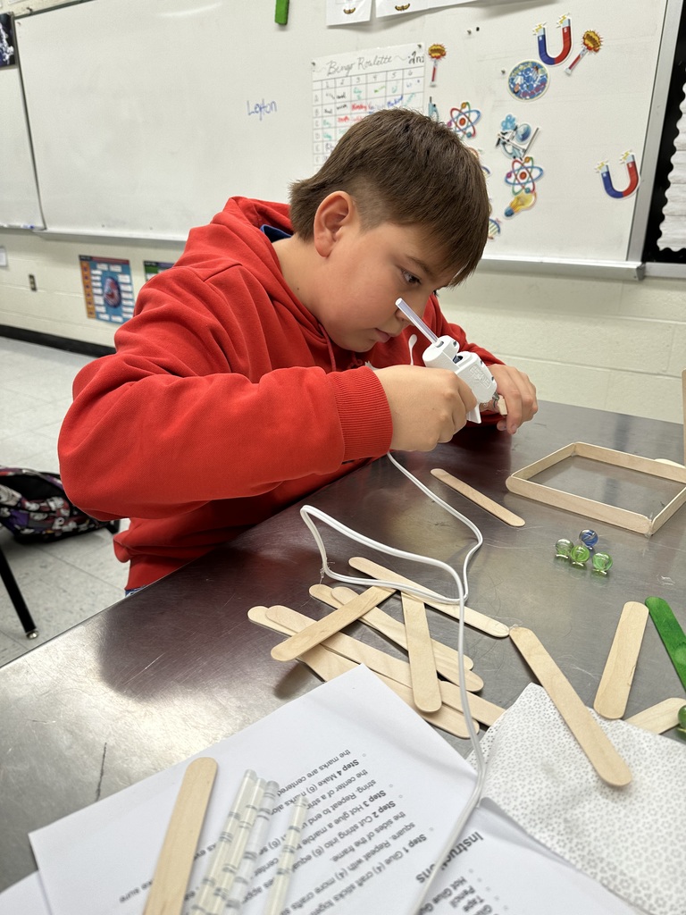 Student gluing popsicle sticks together