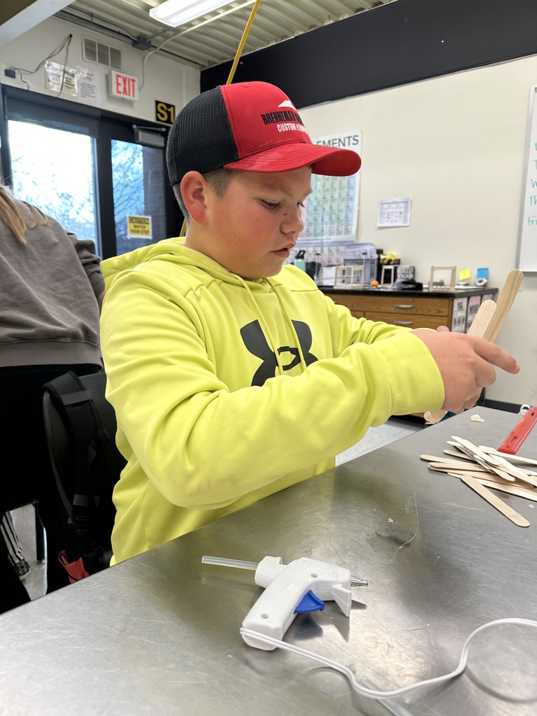 Student gluing popsicle sticks together