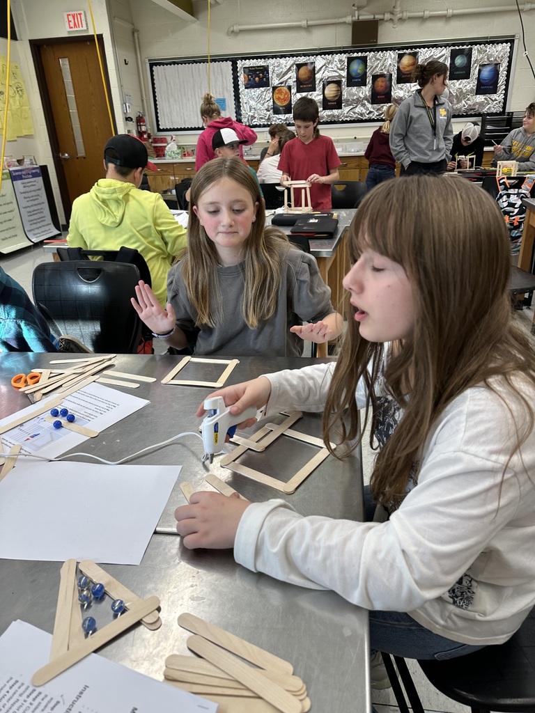 Student gluing popsicle sticks together