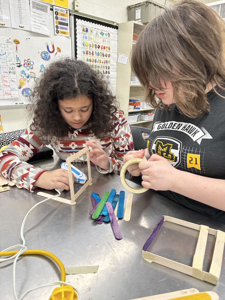 Student gluing popsicle sticks together
