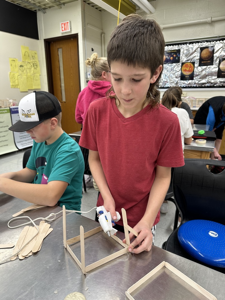 Student gluing popsicle sticks together