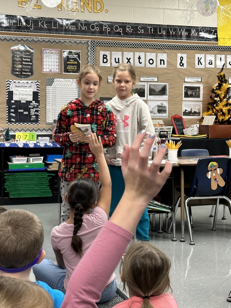 Students reading from a book to the class