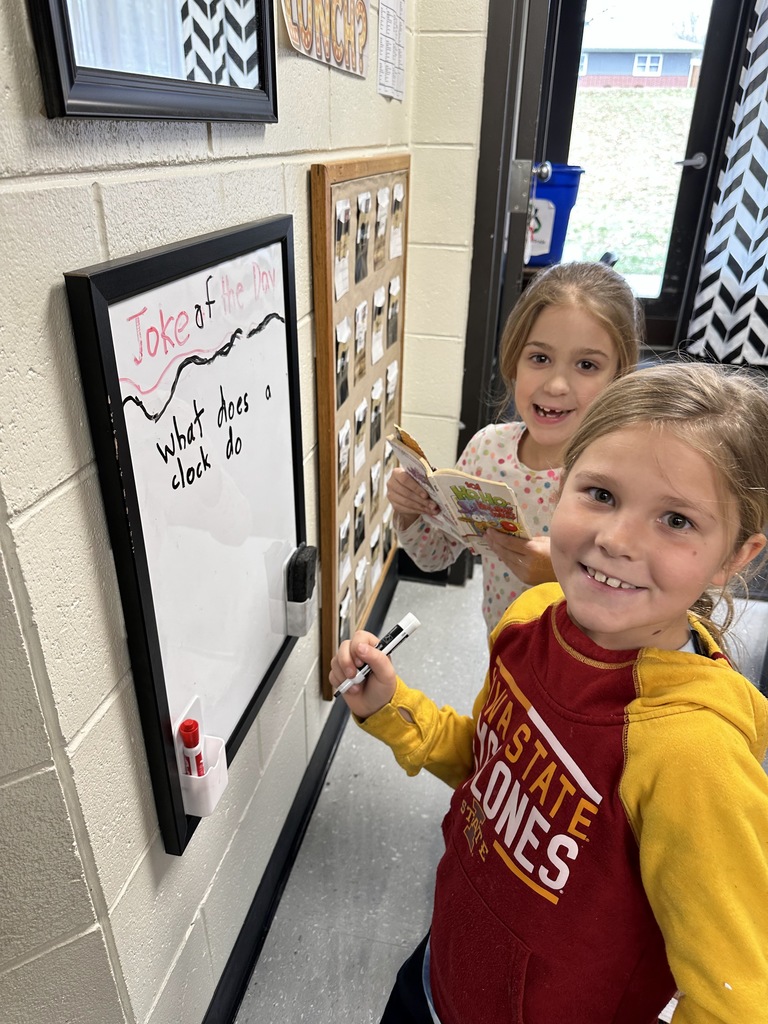 Students writing a joke of the day on a whiteboard
