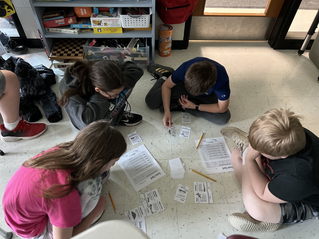 5th graders organizing food chain cards for a science activity