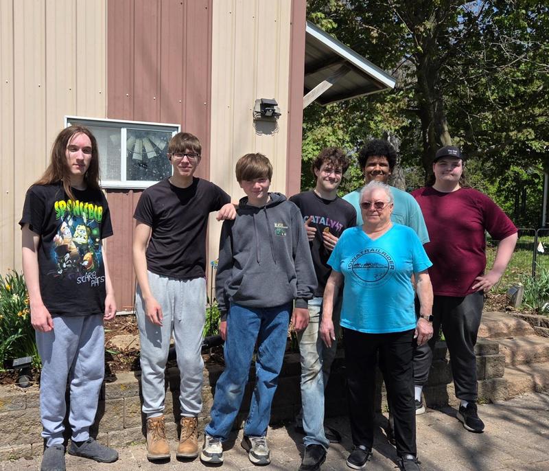 Students standing as a group with "Grandma" outside her home smiling