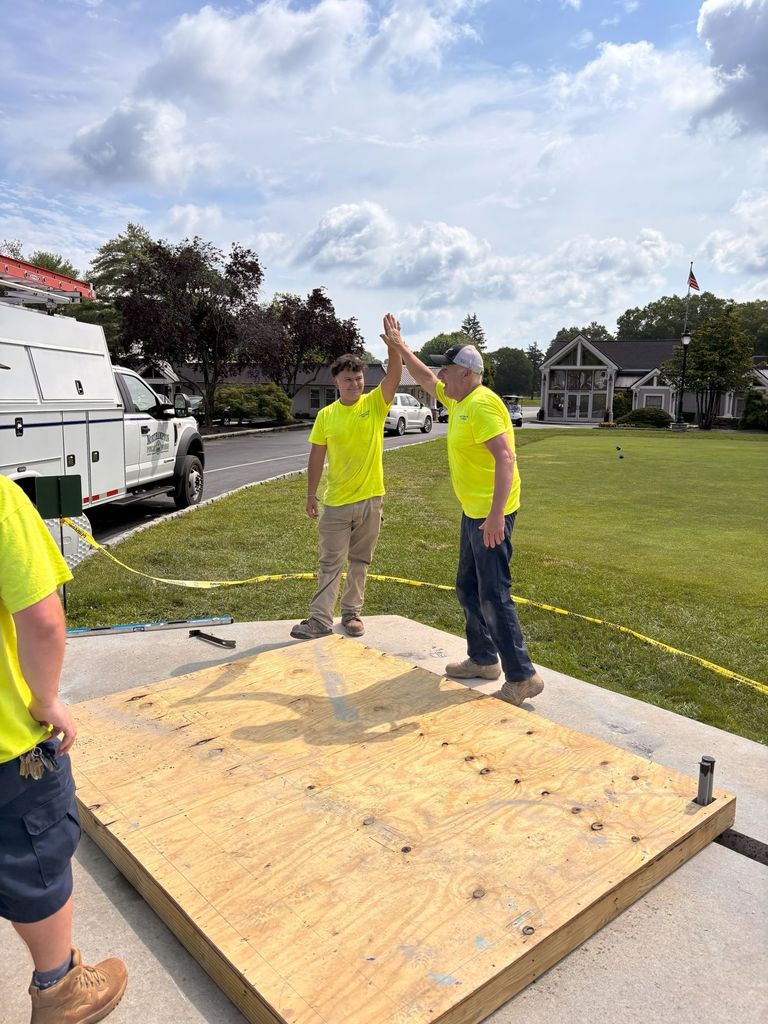 witcher of stevens and mentor high fiving and yellow safety shirts on a wood platform