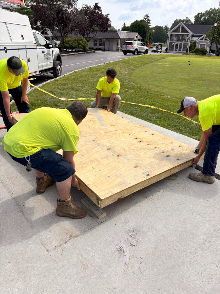 This is a picture of poor workers in yellow safety shirts working on a wood platform