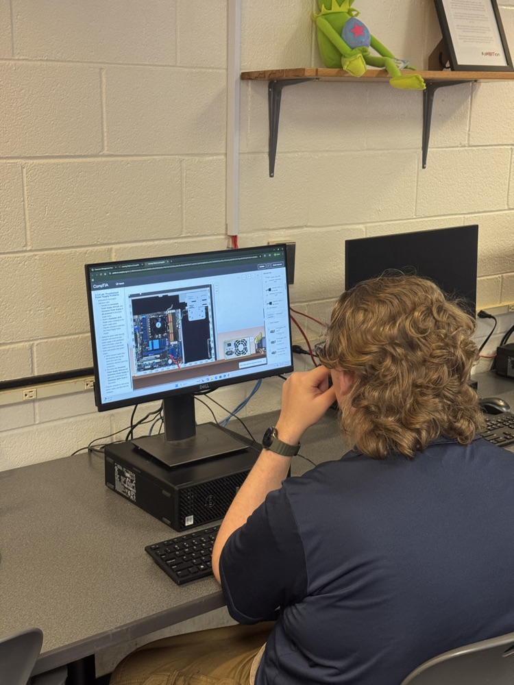 student sitting at a computer looking at a monitor of a computer