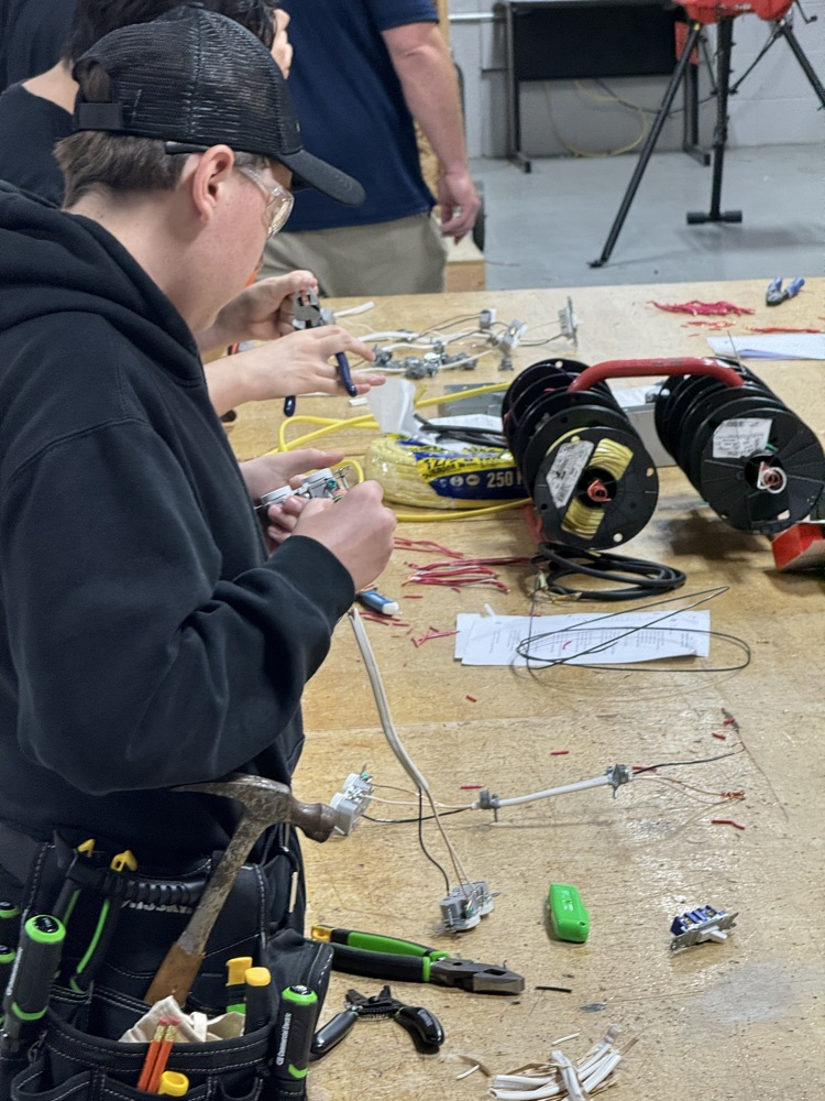 multiple electrical students with safety glasses on and t