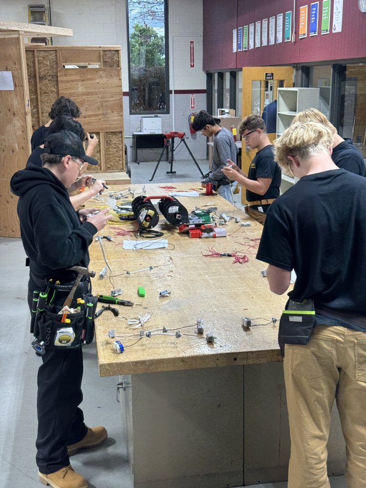 multiple electrical students with safety glasses on and t