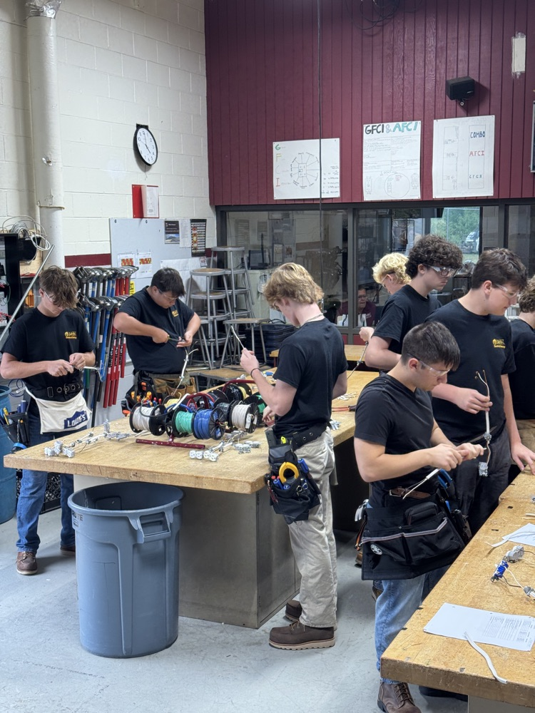 multiple electrical students with safety glasses on and t