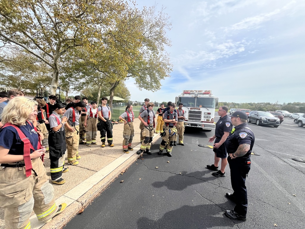 public safety students and the fire in their fire gear talking to the firefighters from the warland fire department in front of the fire truck