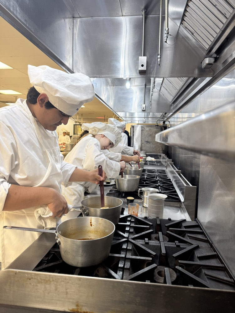 culinary art students cooking on the stove in their uniforms