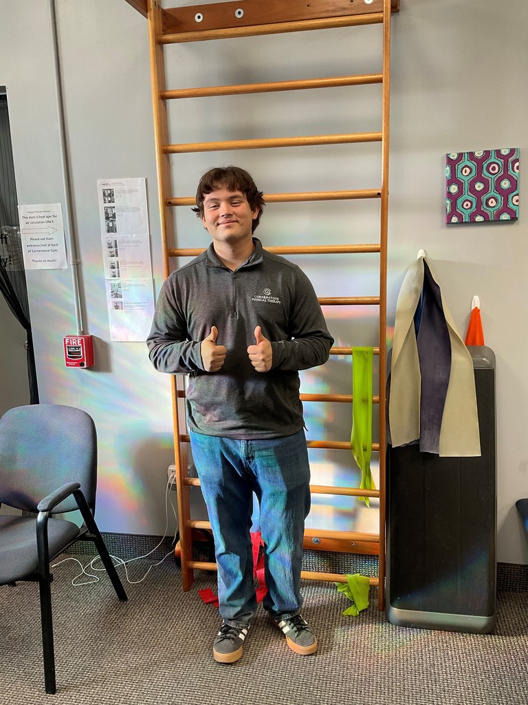 it's a photo of curve it's gonna pair jeans on and a Gray shirt with this thumbs up and a smile on his face he's in a physical therapy room