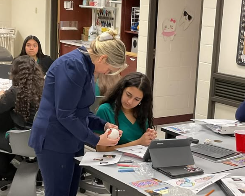 Picture of the teacher helping a student.