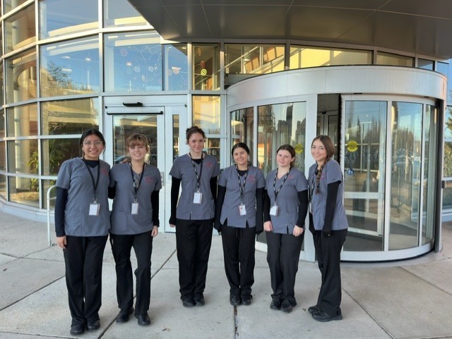 It's a group of medical and health professions students standing in front of Penn Medicine in their scrubs with their badges