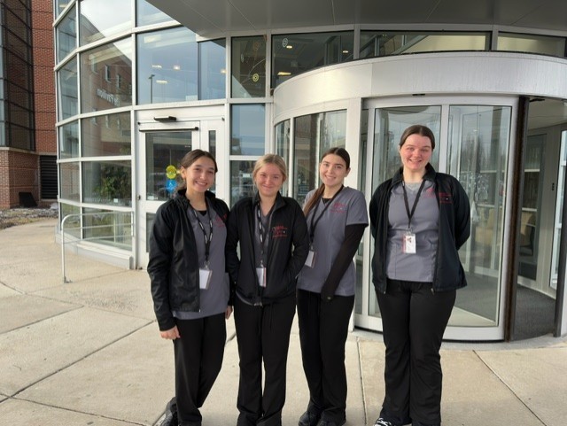 It's a group of medical and health professions students standing in front of Penn Medicine in their scrubs with their badges