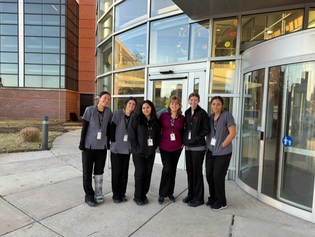 It's a group of medical and health professions students standing in front of Penn Medicine in their scrubs with their badges