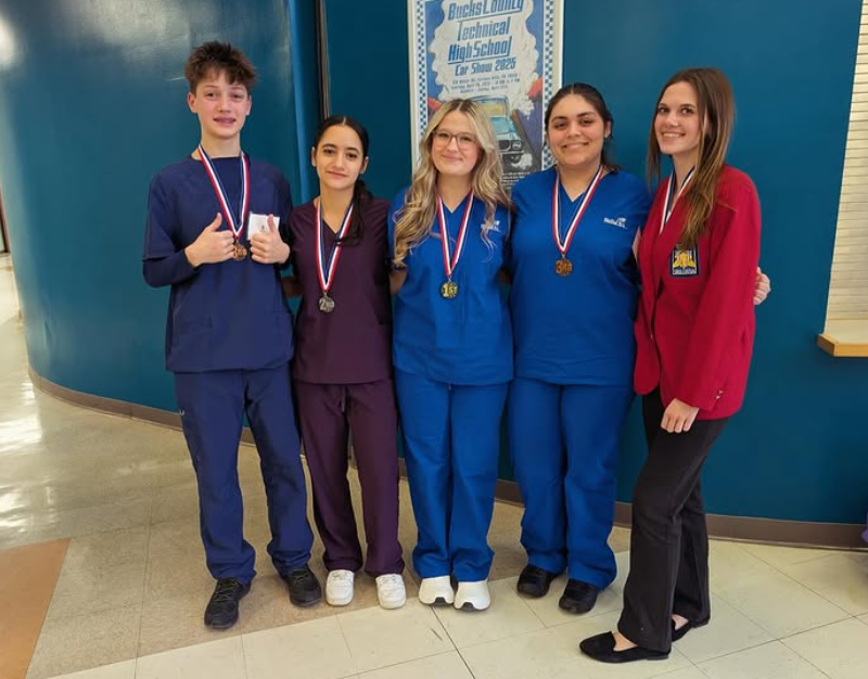 The group photo of medical students and one student in her skills. USA red jacket with their medals around their necks with smiles on.
