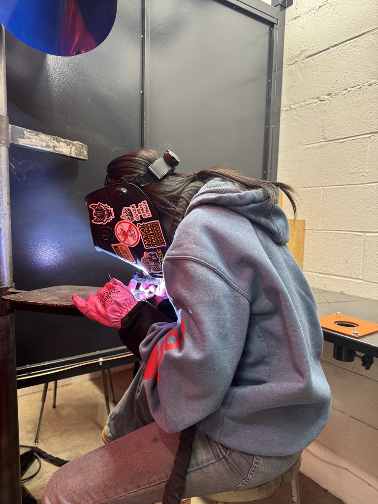 This is a female wedding student. She's got her helmet down blue, our pink gloves on she's welding