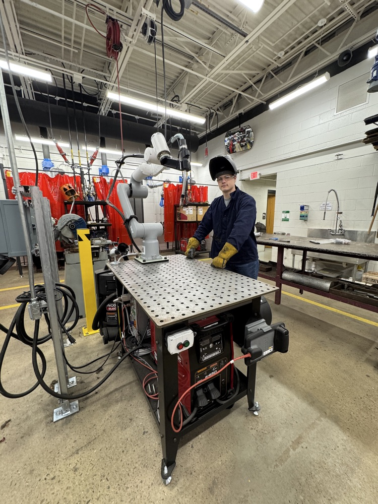 it’s a welding student in front of the robotic welding machine