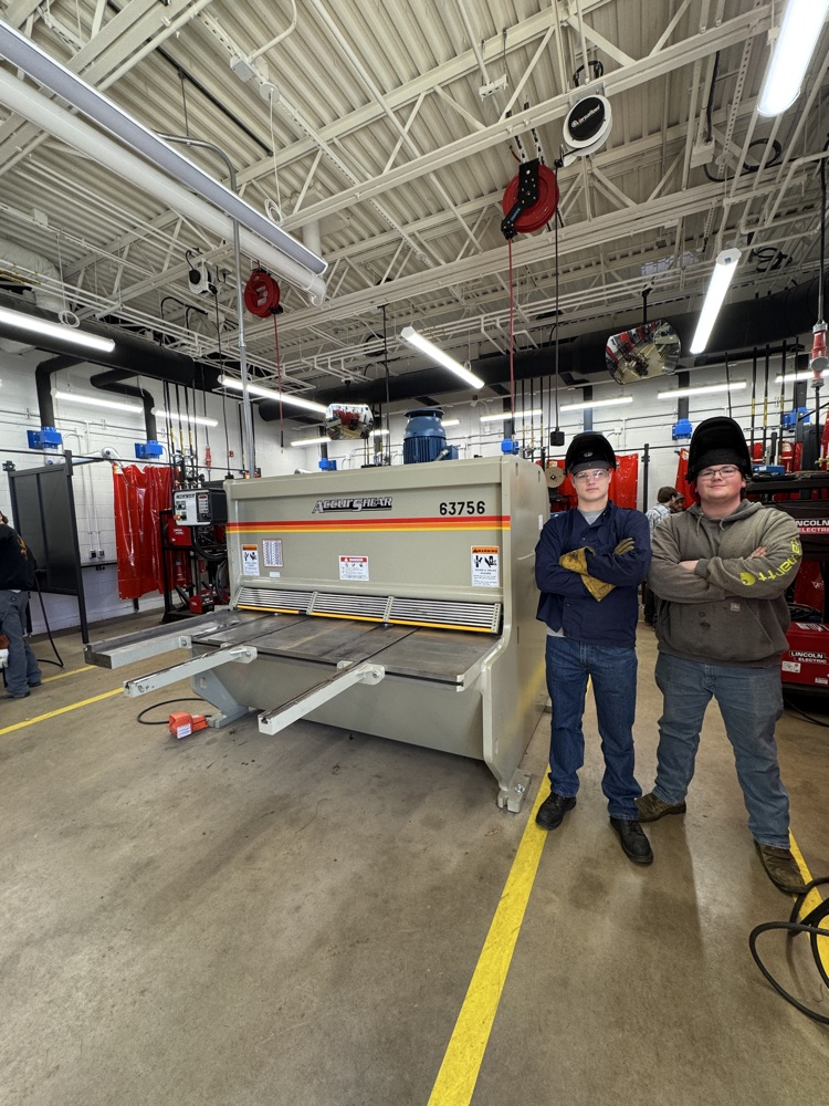 two voting students next to the metal shear