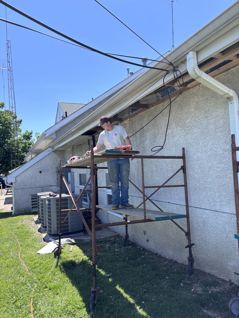 The student standing on some scaffolding by a house