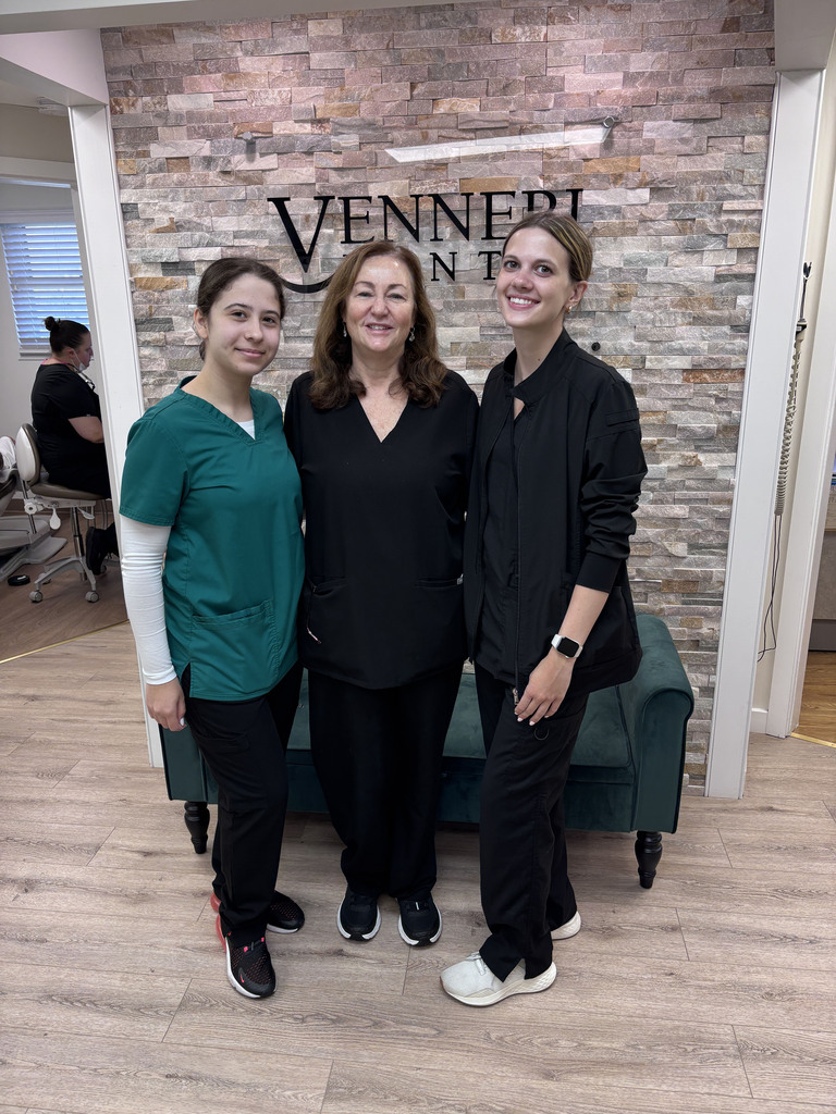 Shot of the two students and the dentist standing in front of their signs on their basis and wearing scrubs