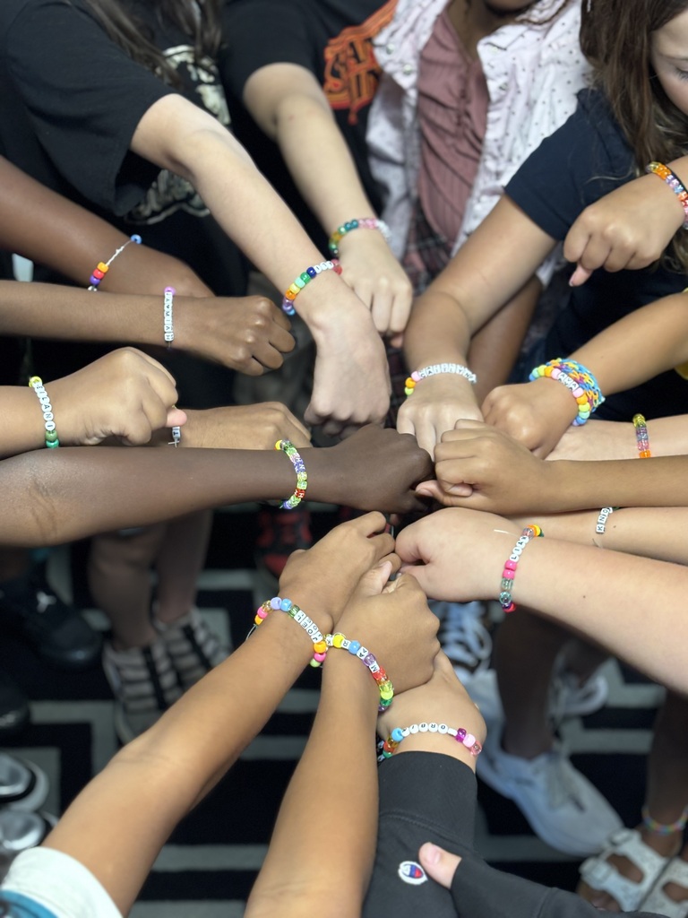 A group of hands all together with bracelets featured.