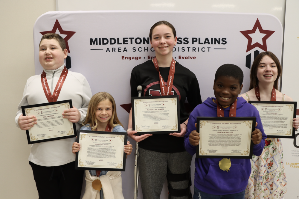 Nolan Mikla, Charlotte Henry, Natalie Laschinger, Jordan Walker, and Molly Marshall standing in front of a photo backdrop and smiling while holding their Cardinal's Journey Awards