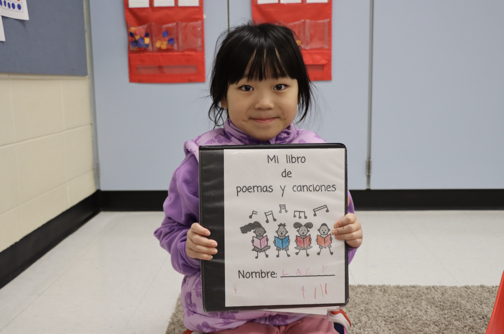 Student smiling and holding a folder with poems and songs