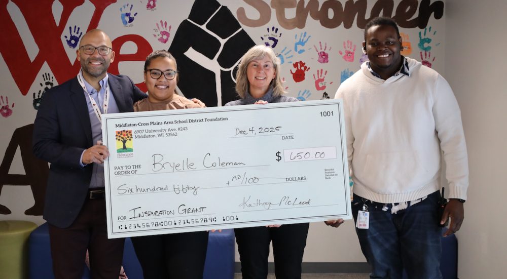 Grant winner Bryelle Coleman holding an oversized check with award presenters