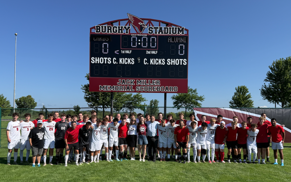 Soccer players in front of Jack Miller Memorial Socreboard
