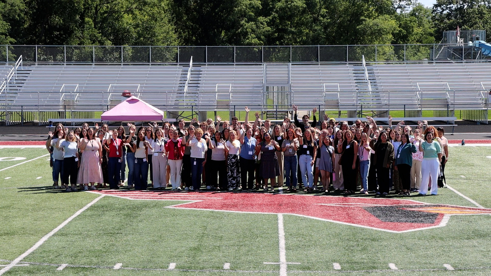 MCPASD staff smile and wave while standing on the football field