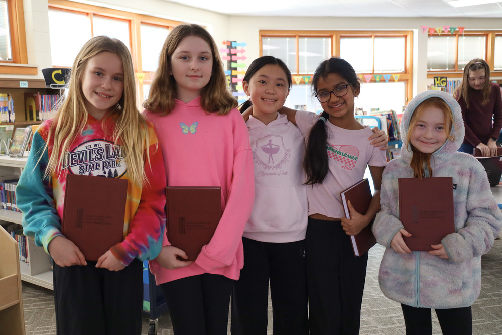 Sauk Trail Elementary School students smiling and holding notebooks after newsletter meeting