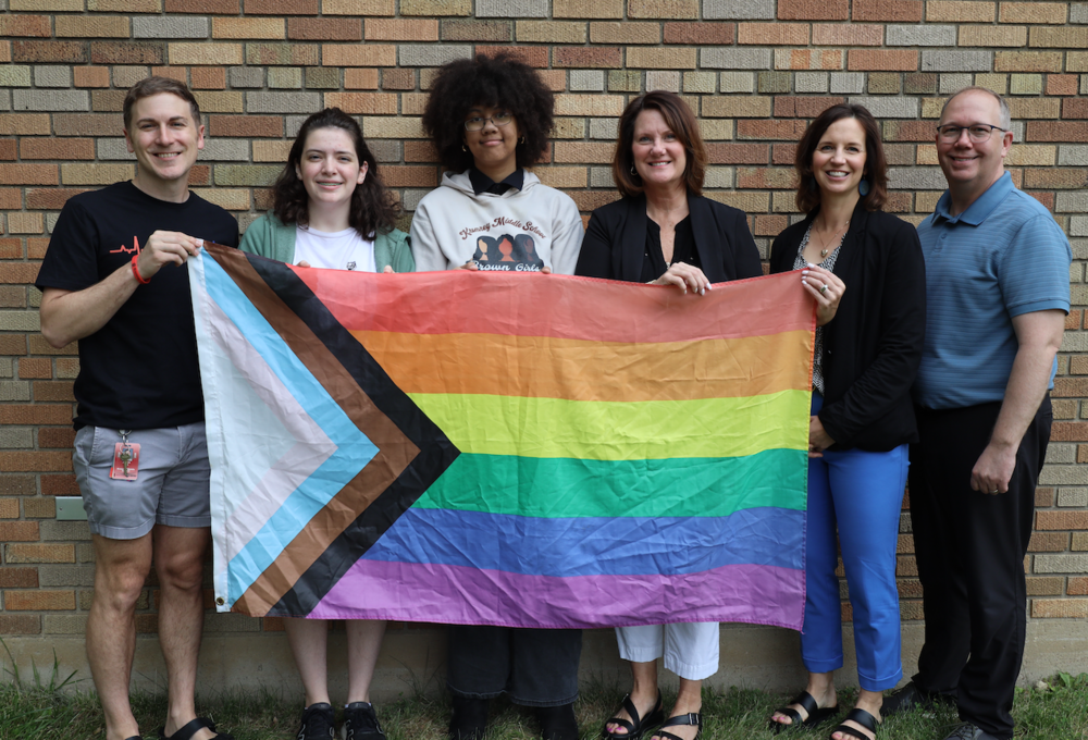Students, staff and administrators holding the Pride flag