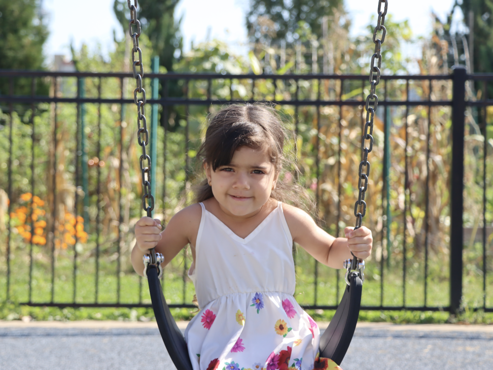 4K student wearing a floral dress and smiling while on a swing
