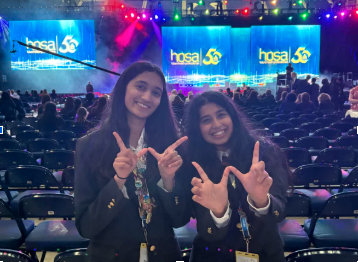 Two students posting by HOSA stage