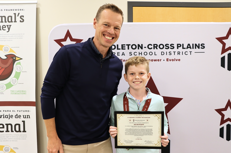 Jacob Roepe smiling standing next to his dad and holding his Cardinal's Journey Award