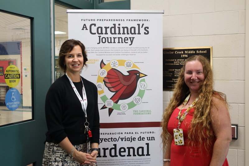 Dr. Jan Chynoweth and Tabitha Hansen standing by a banner featuring A Cardinal's Journey