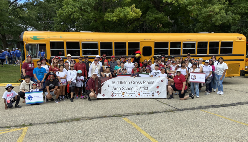 MCPASD staff, parents, and students holding an MCPASD banner that says "Engage. Empower. Evolve." before the 2025 Good Neighbor Fest Parade