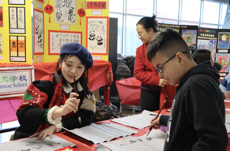 Students and staff smile while working on calligraphy during the Middleton High School Lunar New Year celebration