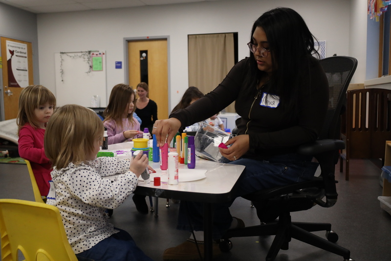 High school student helping children paint pictures